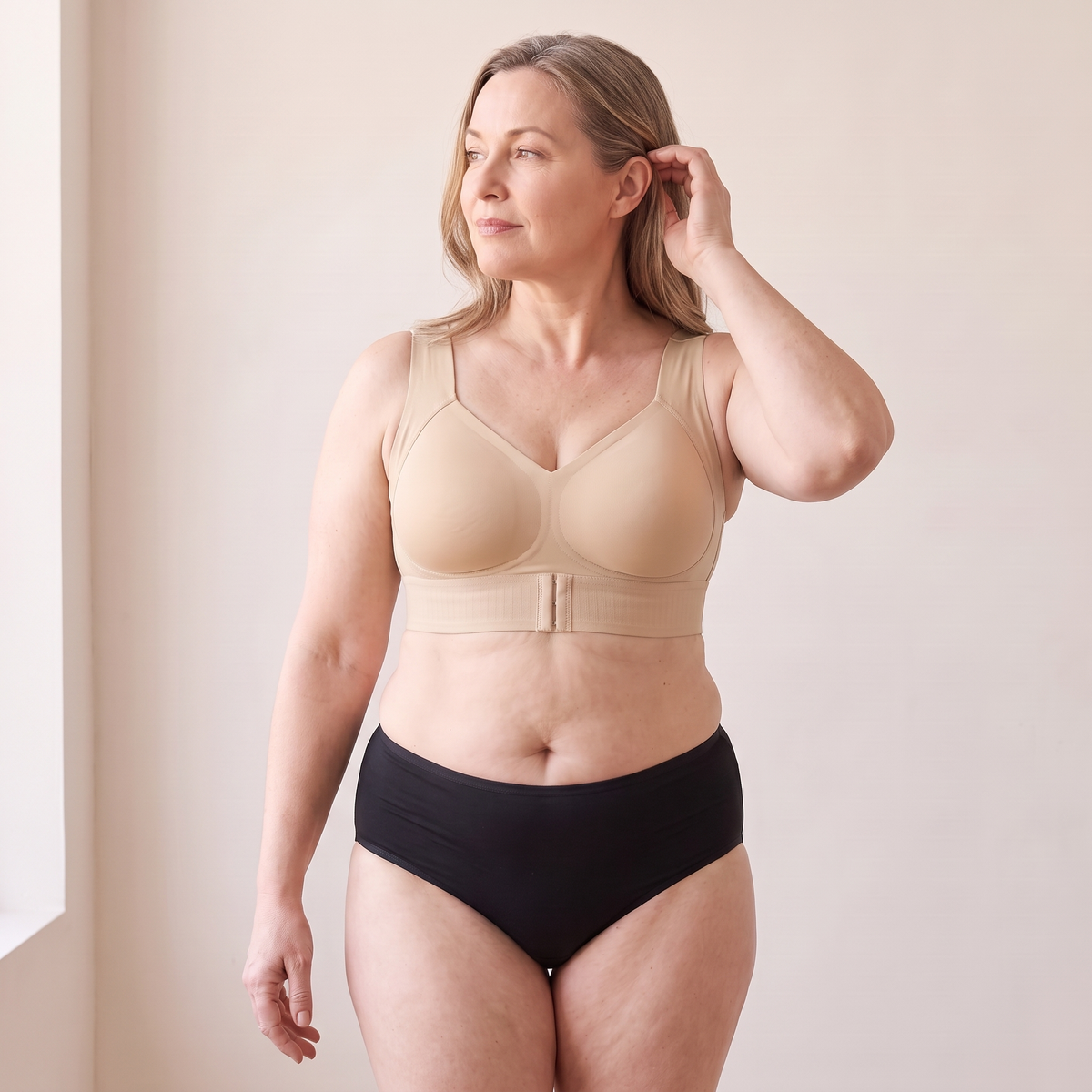 Soutien-gorge MUE beige porté par un mannequin adulte d’environ 48 ans à la silhouette généreuse, main ramenant les cheveux derrière l’oreille — visuel généré.